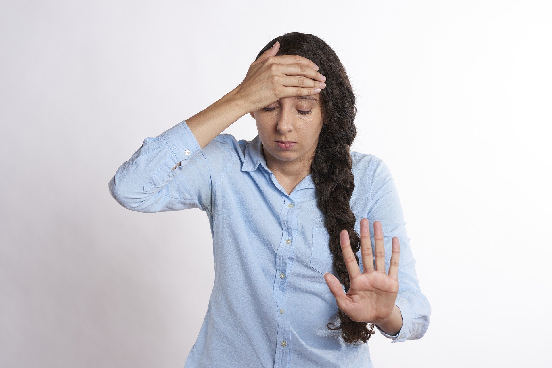 A woman with her hand on her head and a hand up to indicate 'no more' for a post about maternal mental overwhelm.