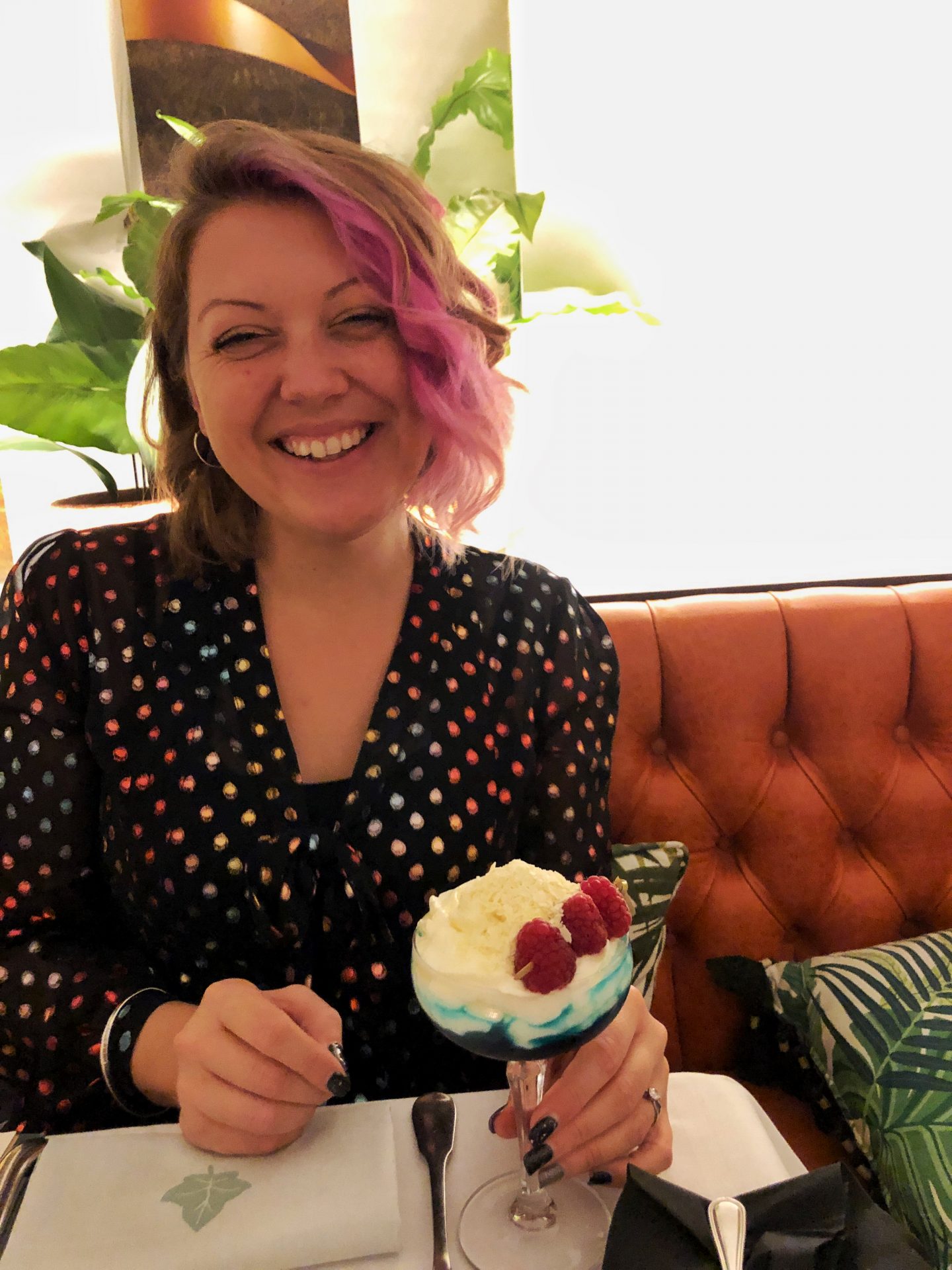 A photo of me out, smiling with a cocktail in front of me, migraines mean I have to be careful with alcohol.