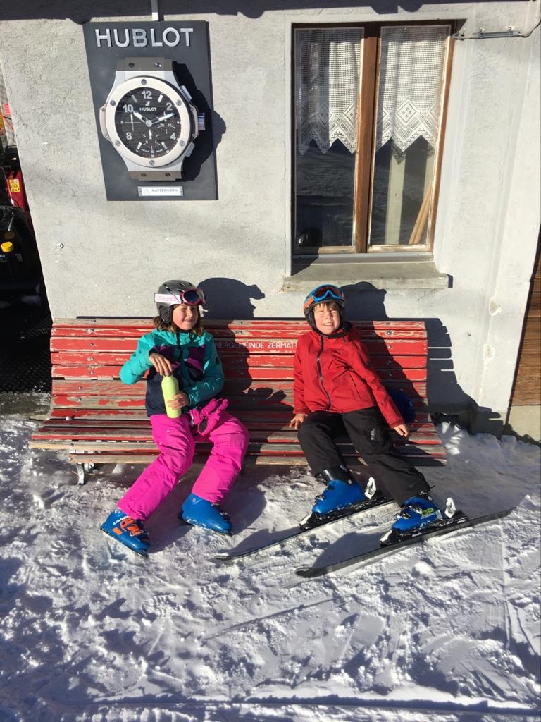 The children rest on a bench during a morning skiing.