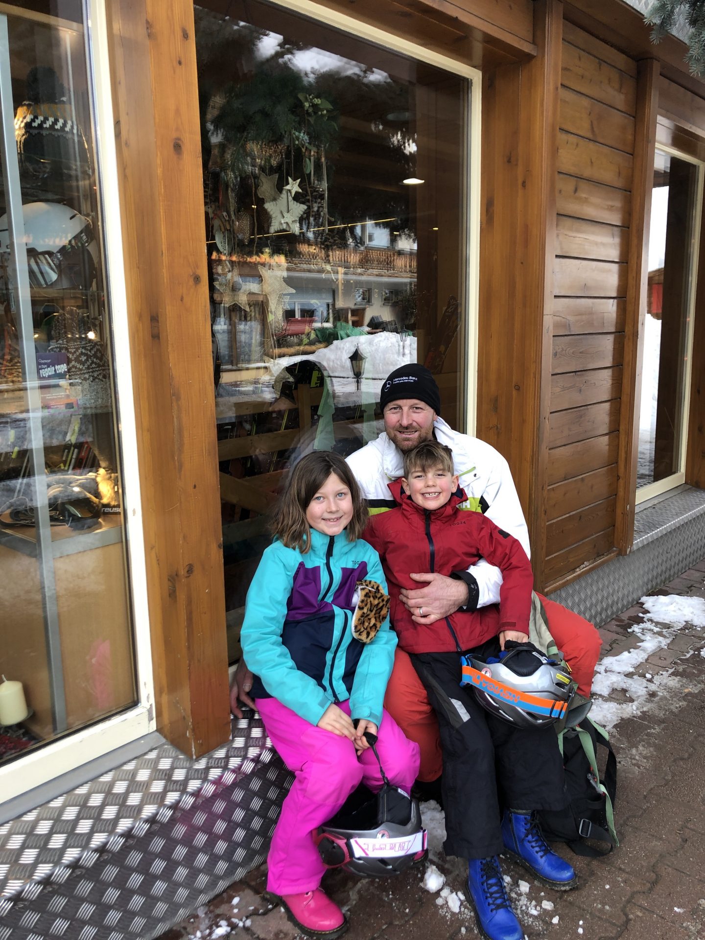 The family sit and pose outside FlexRent ski hire in Zermatt.