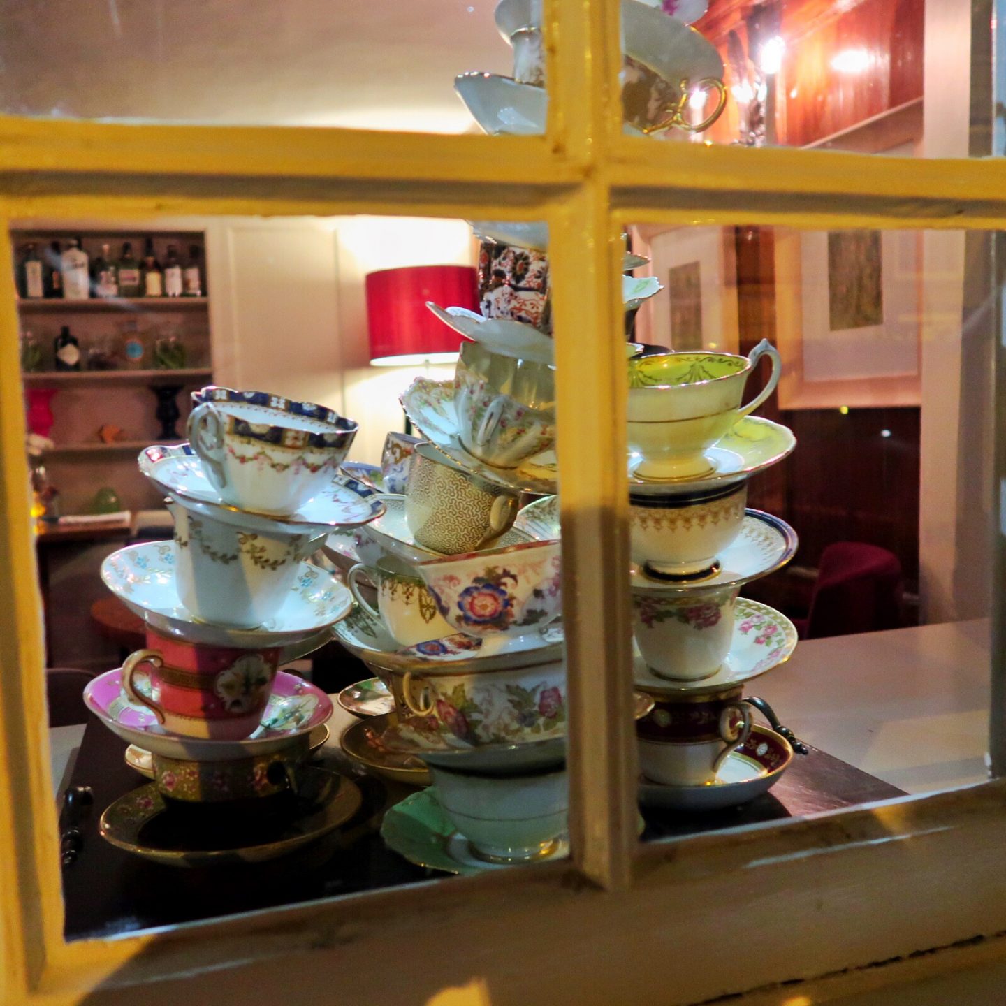 A display of tea cups and saucers stacked up in the window of The Feathers Hotel.