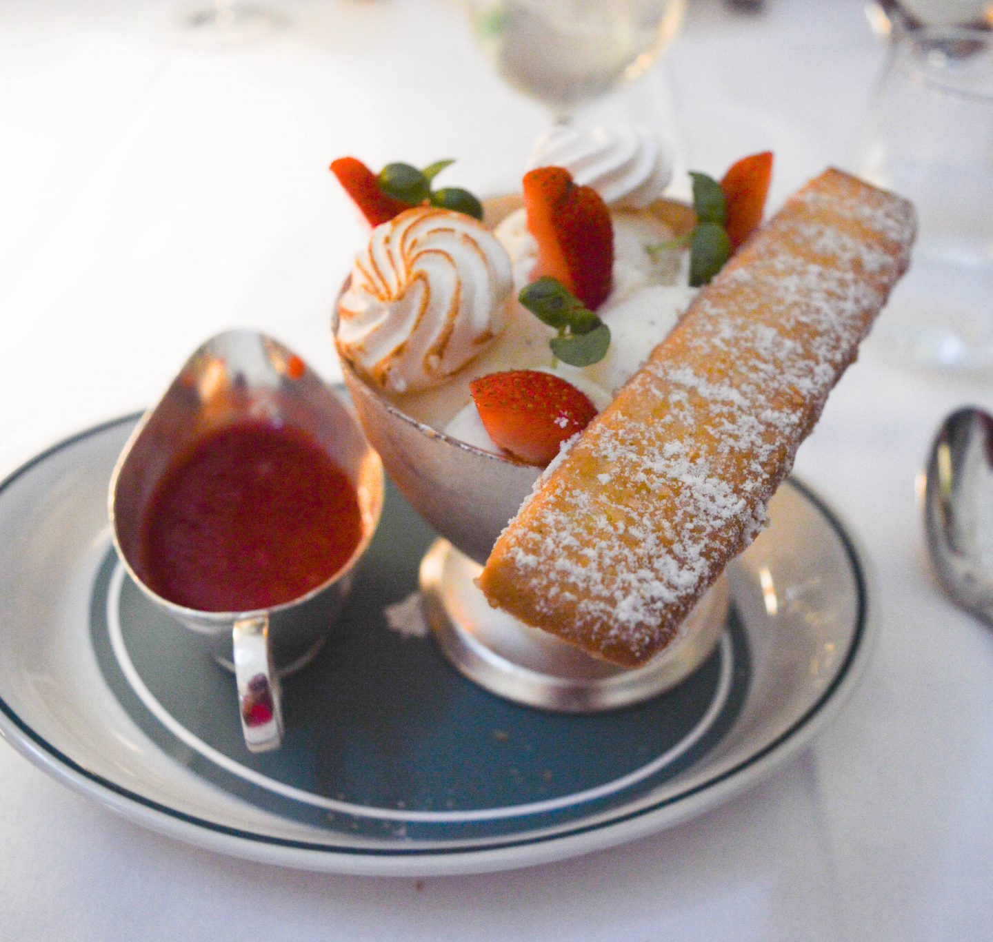 Strawberry ice cream sundae with pouring sauce and homemade shortbread.