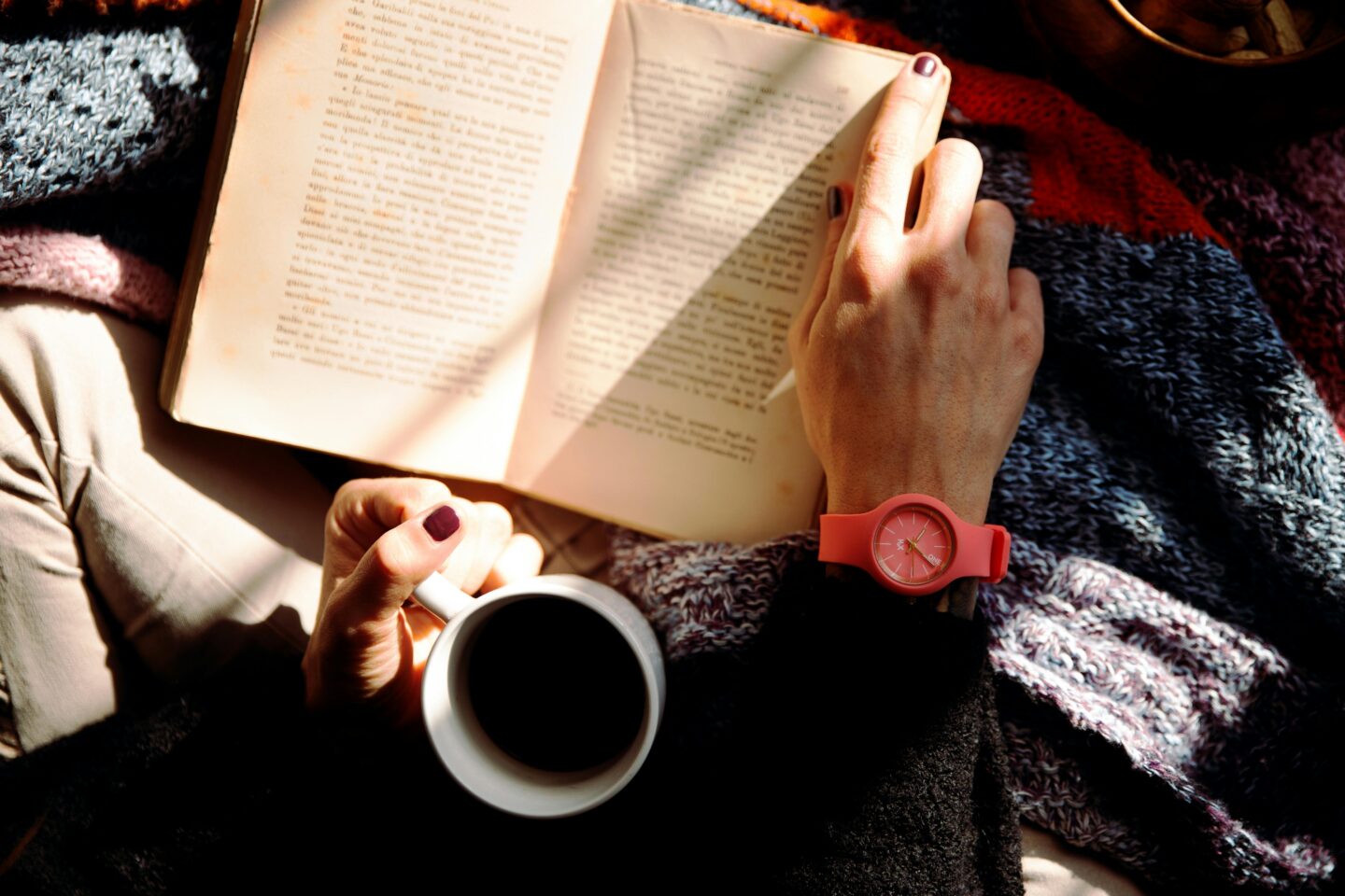 A photo taken from above of hands holding a book open and a cup of coffee for a post about the best Some of my favourite Autism / Trauma/ ADHD Books for adults.